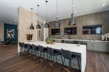 a large kitchen with a white counter top and chairs
